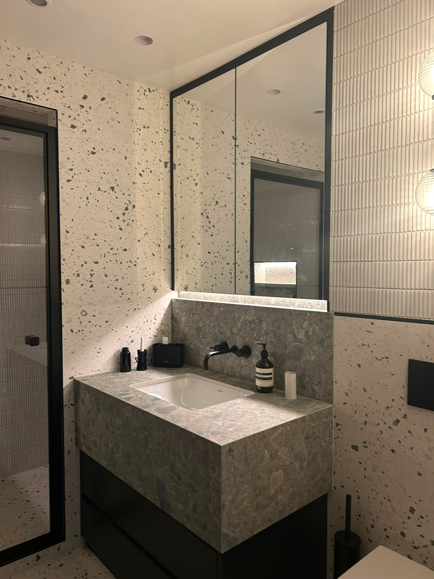 Contemporary terrazzo bathroom with backlit mirror and recessed lighting on a smart home control system in Derby