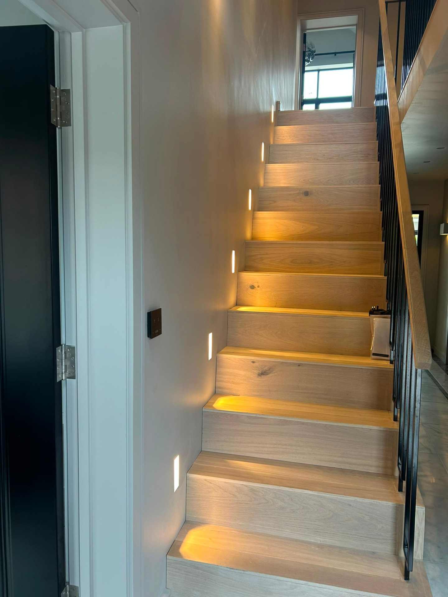 Recessed vertical wall lights illuminating a wooden staircase in a completed R Electrical Solutions project