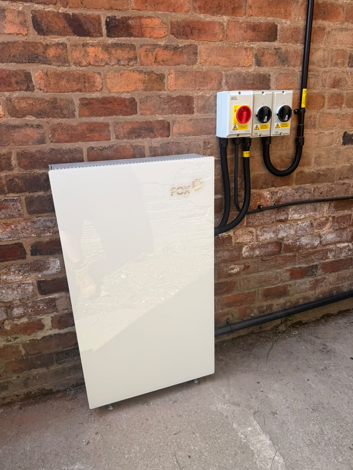 Fox ESS home battery storage unit with isolators and armoured cabling installed on a brick wall