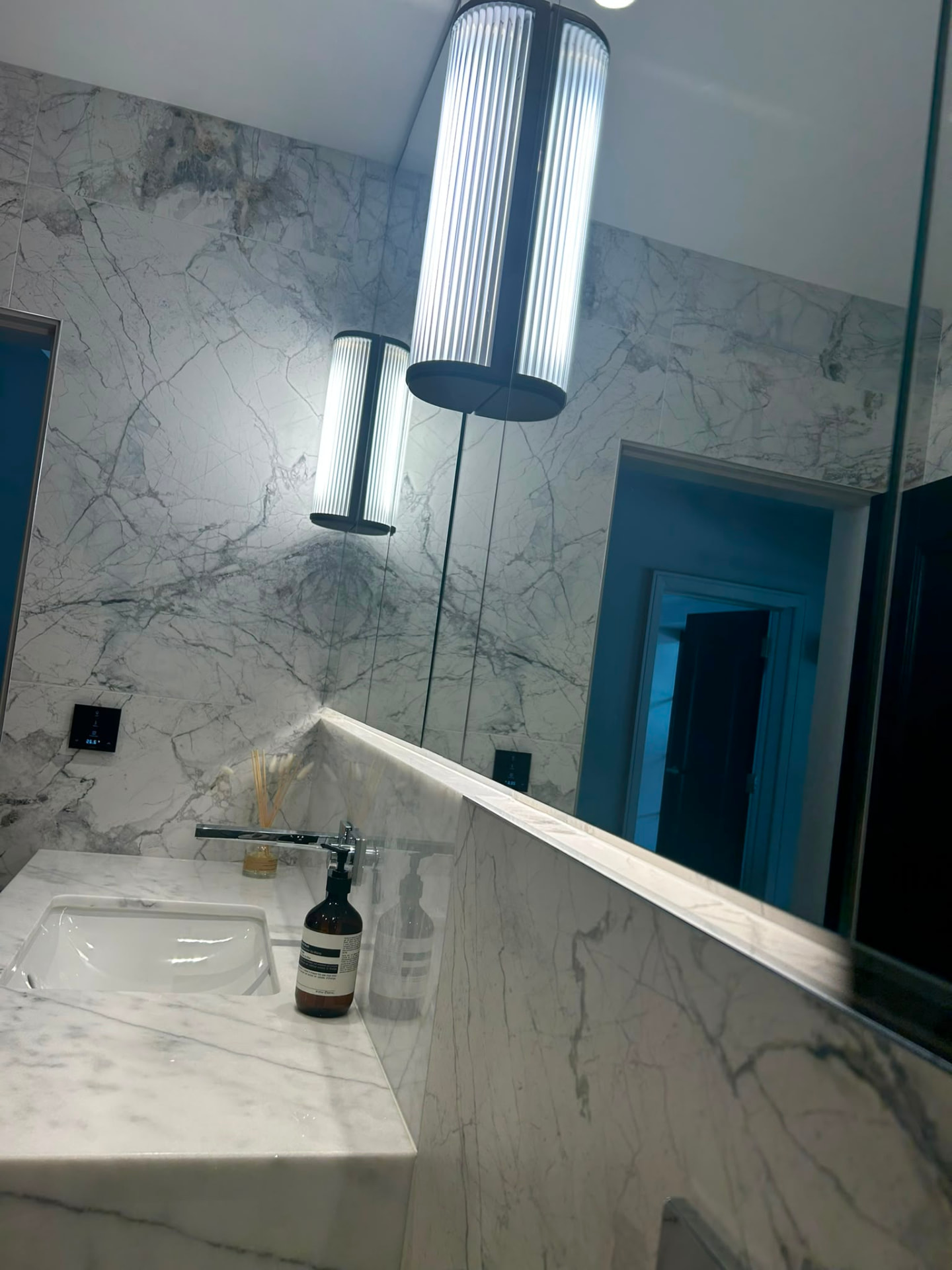 Marble-tiled bathroom vanity with an integrated vertical LED feature light