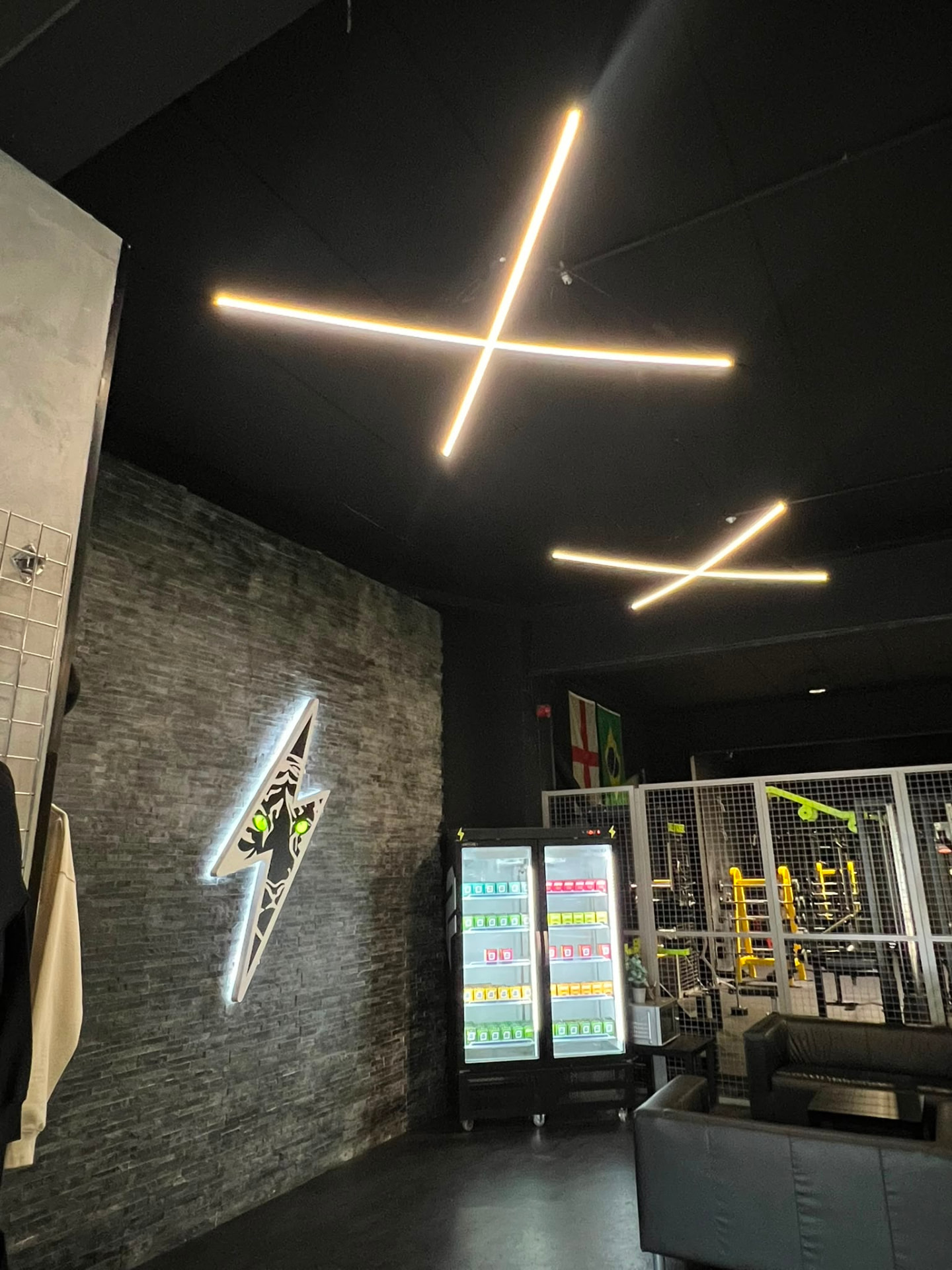 Minimalist X-shaped LED ceiling lights installed in a commercial gym space
