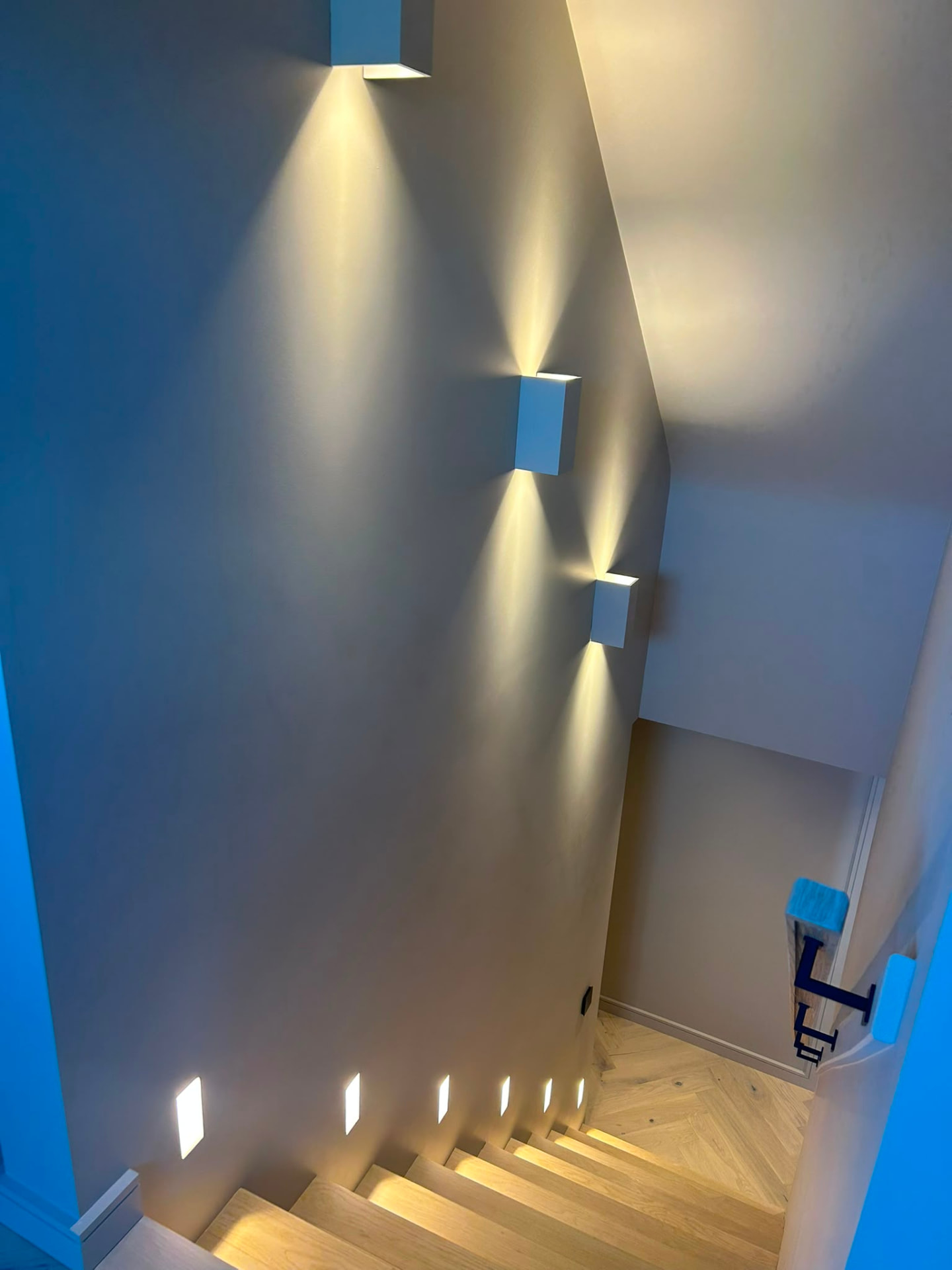 Staircase lighting with wall-mounted uplights and recessed step lights